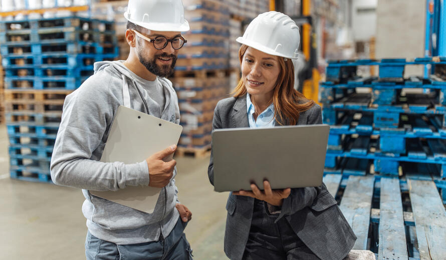 people looking at a laptop on a manufacturing floor