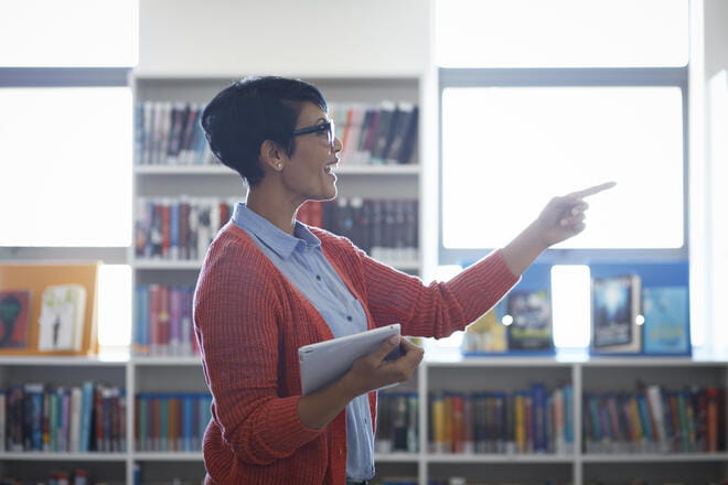 Teacher talking to students, in the library