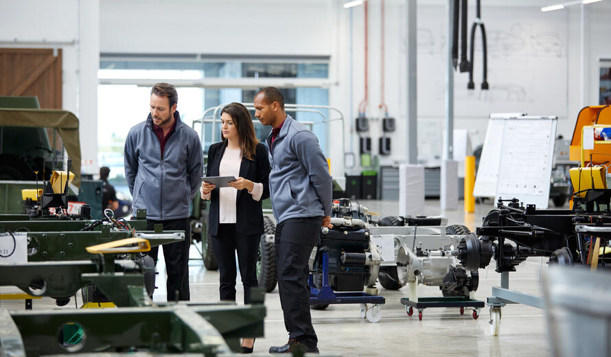 Automobile engineers and supervisor looking at incomplete vintage car.
