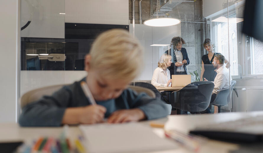 Boy painting in office with business team having a meeting.