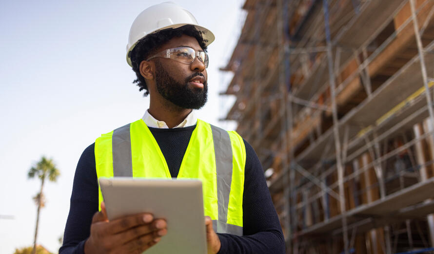 A young black man is a project manager at a residential construction site.