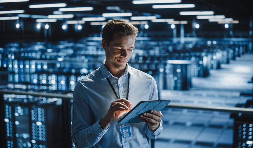 Portrait of Smiling IT Specialist Using Tablet Computer in Data Center.