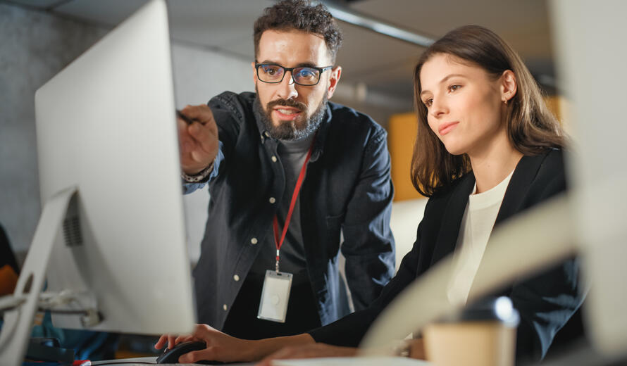 Image showing two individuals reviewing and pointing at content on a computer screen.