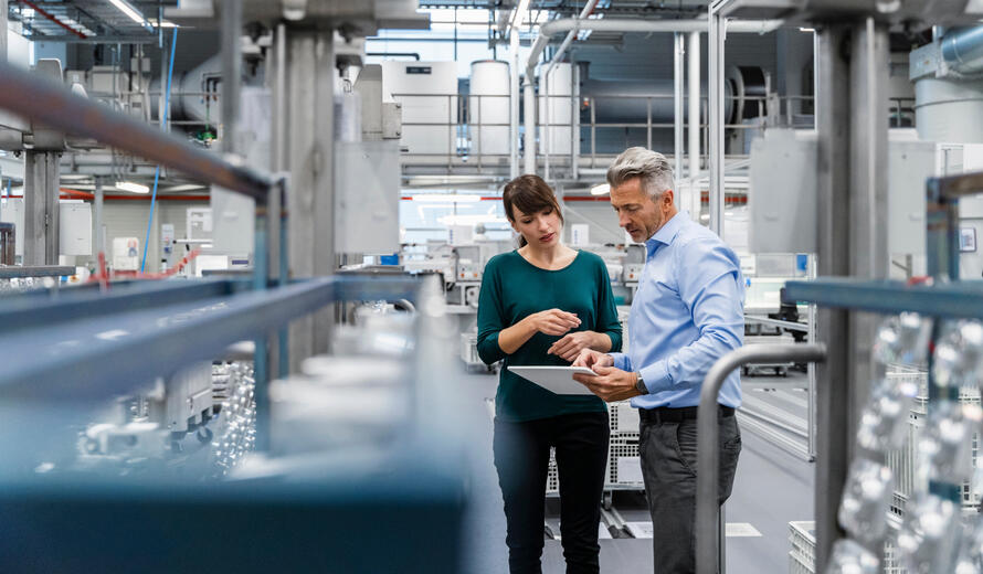 Businesswoman discussing over tablet PC with coworker at factory.