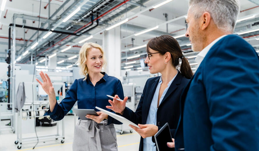Businesswomen having discussion by businessman at automated factory.