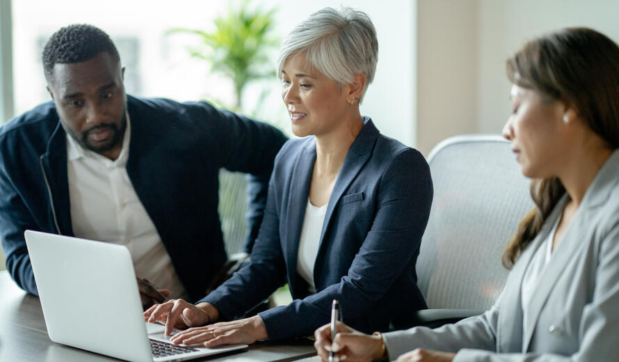 A small group of three adult business professionals meet to discuss new strategies for the company. 