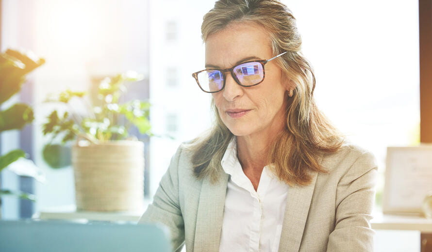 Mature business woman working on laptop in an office. Focused entrepreneur and dedicated leader with glasses browsing online for ideas and inspiration while planning for success in a startup company