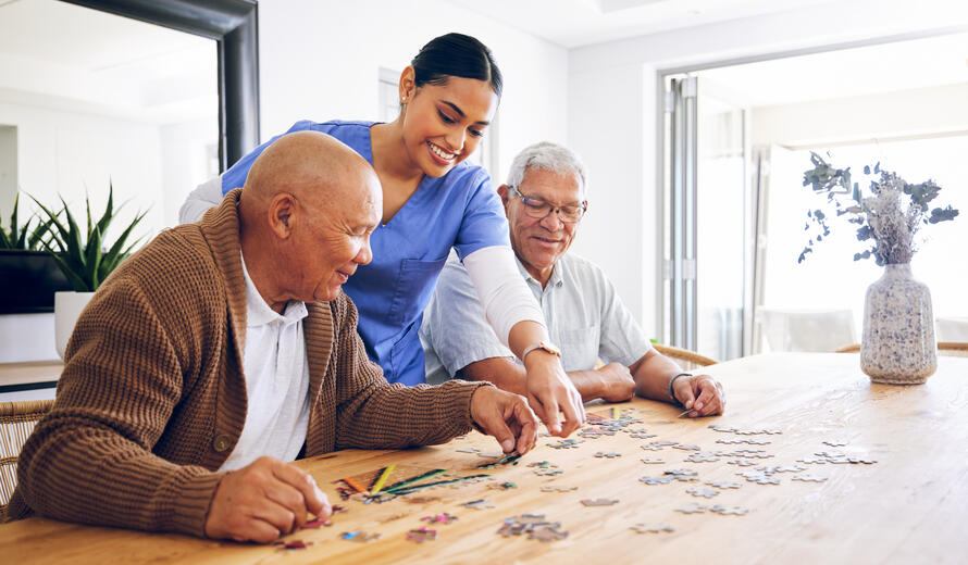 Puzzle, caregiver and senior men playing a game as entertainment or bonding together in a retirement home. Happy, fun and elderly people enjoy mental rehabilitation and development with nurse