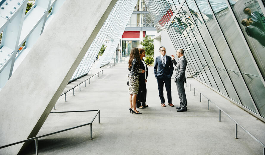 Businessman leading informal meeting with colleagues in outdoor corridor of office building