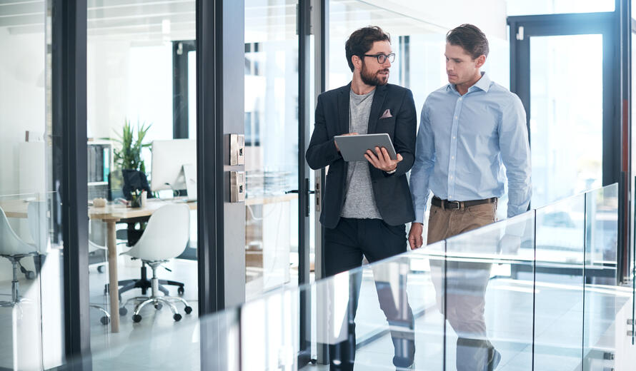 Shot of two businessmen using a digital tablet together in an office