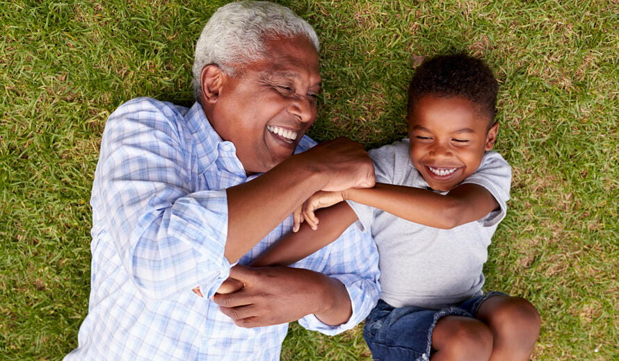 Grandfather and grandson play lying on grass, aerial view