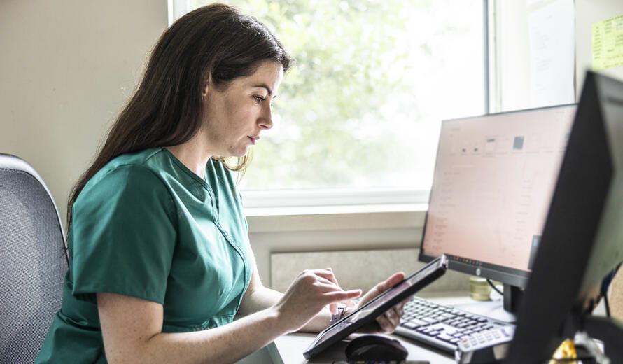 Nurse in scrubs working at desk in doctor's office