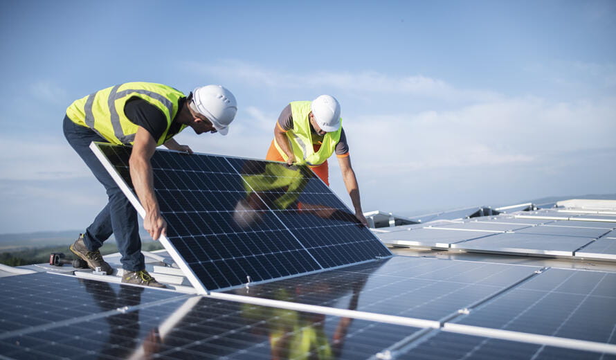 Team of two engineers installing solar panels on roof