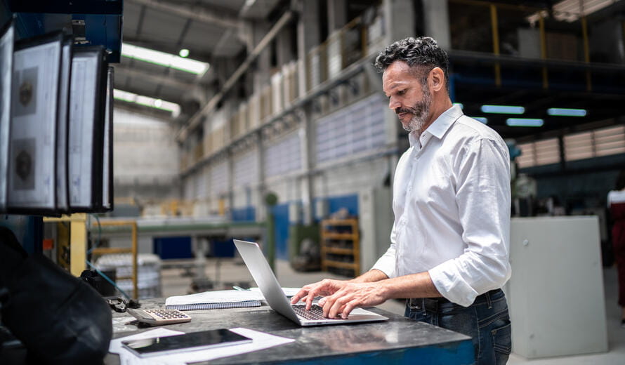 Mature businessman using laptop in a factory
