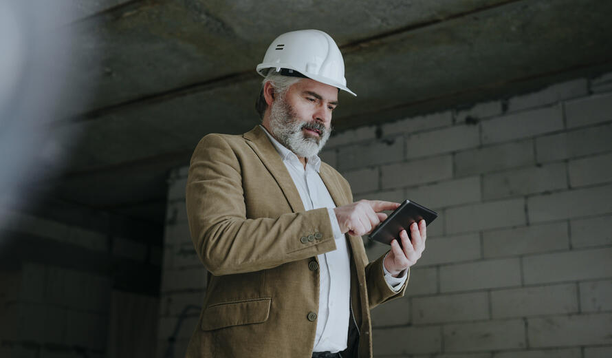 a man wearing a hard hat and holding a tablet