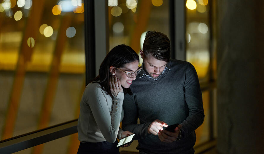 Young entrepreneurs reading a text message on smart phone while working late in the office.