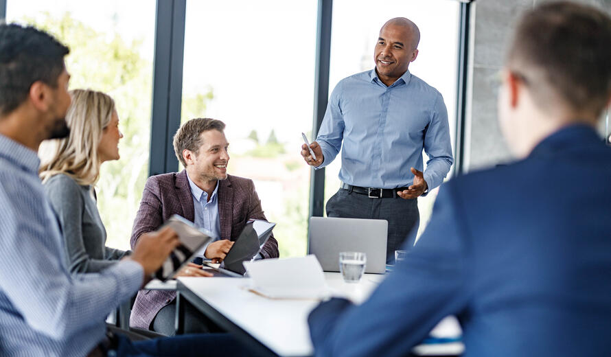 Happy black businessman giving a speech to his colleagues during a meeting in the office.