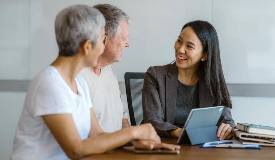 A multiethnic senior couple is signing a business agent agreement with an estate investment consultant during a meeting
