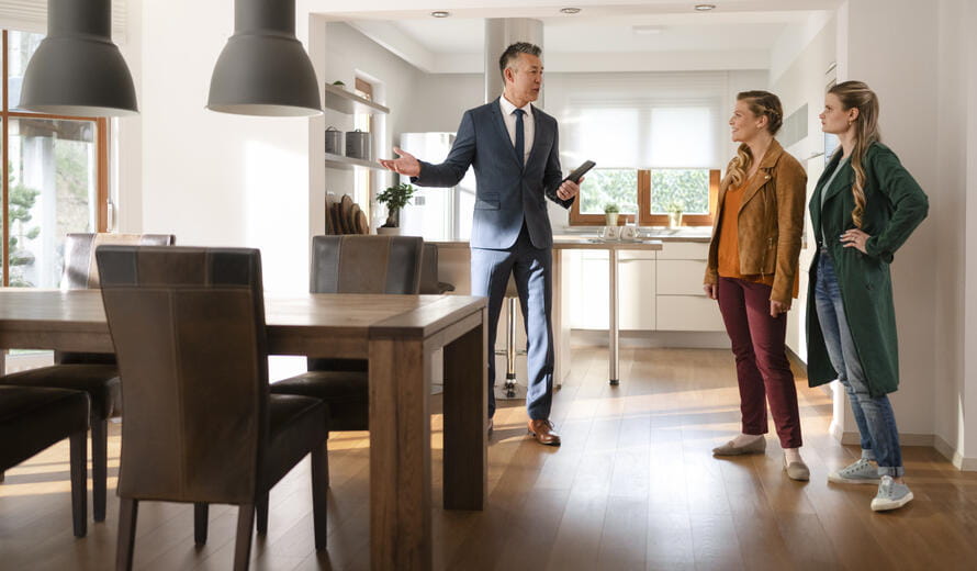 Male real estate agent showing modern luxury house to women.