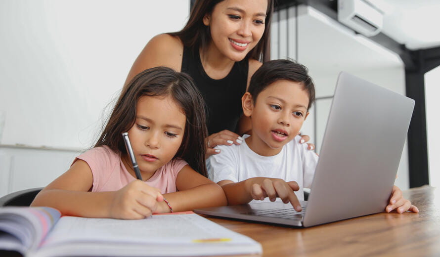 Close-up shot of Indonesian Mother Homeschooling Children at Home. Her daughter and son doing homework together in dining room.
