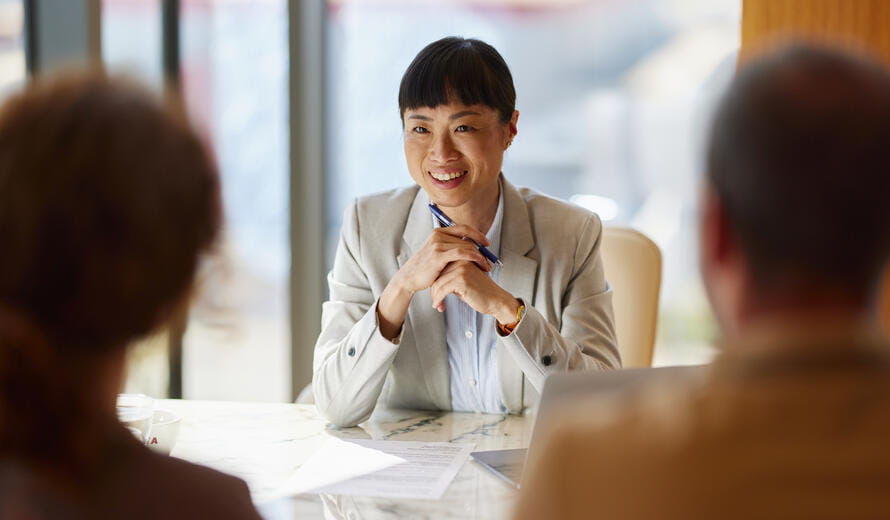 Happy Asian bank manager communicating with her customers during a meeting in the office.