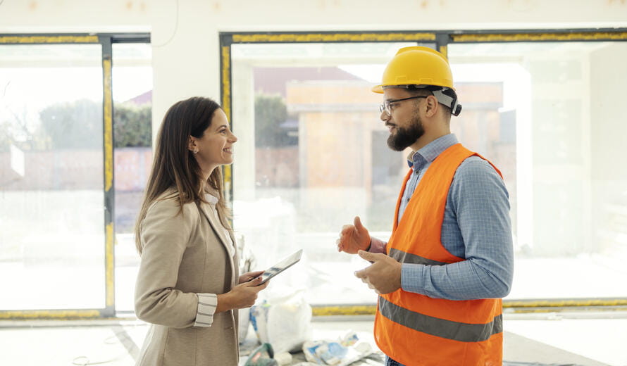 Side view of colleagues engineers with tablet discussing in building in building process.