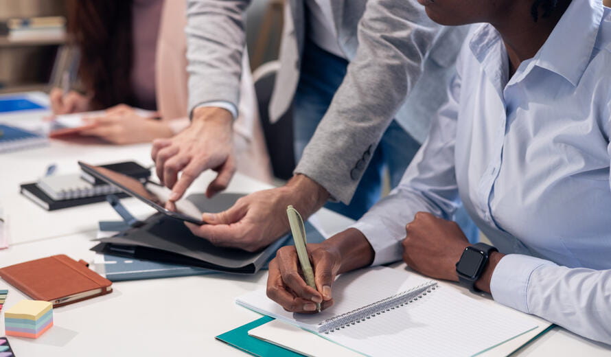 Business colleagues collaborating and discussing ideas using a tablet and notebook during a meeting