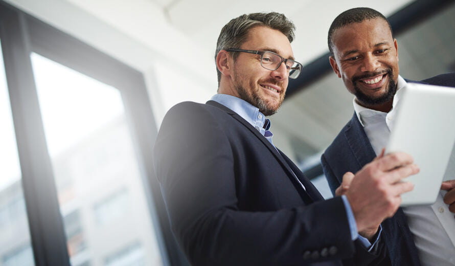Shot of two businessmen using a digital tablet together at work