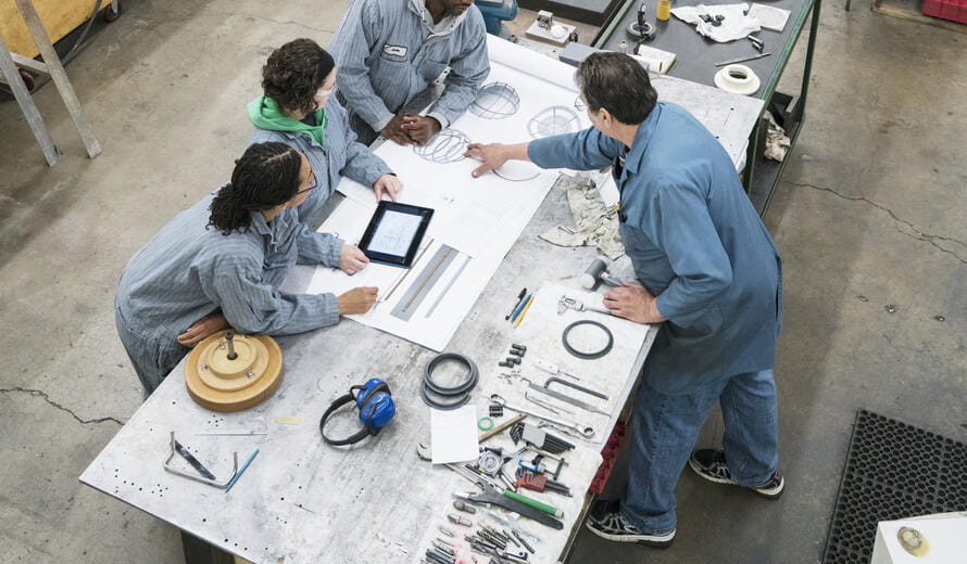 Workers examining blueprint in factory